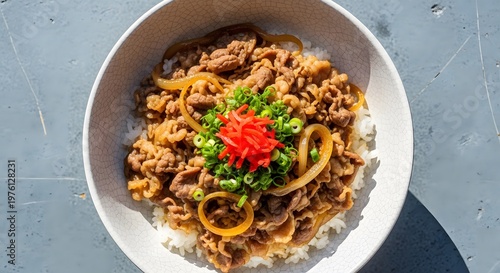 Traditional japanese beef bowl gyudon topped with fresh green onions and pickled ginger red.