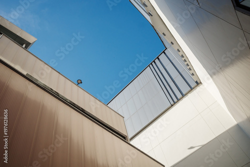 Low angle architectural photograph of modern building exteriors with geometric lines against a bright blue sky