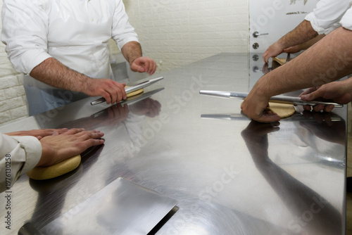 Workers at a Jerusalem matzah bakery use metal rolling pins to flatten chunks of dough into round sheets of matzah prior to baking the unleavened bread for the Jewish holiday of Passover in Israel.