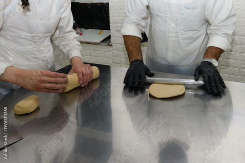 Fotografie Workers at a Jerusalem matzah bakery use metal rolling pins to flatten chunks of dough into round sheets of matzah prior to baking the unleavened bread for the Jewish holiday of Passover in Israel