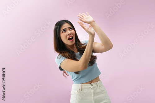 Φωτογραφία Indonesian woman raising both hands above head with scared expression as if avoi