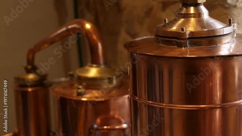 Copper absinthe still in distillery with warm light and metal reflections