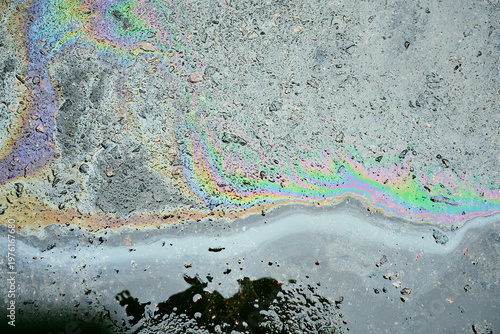 Iridescent oil slick pollution creating beautiful rainbow colors on dark wet asphalt