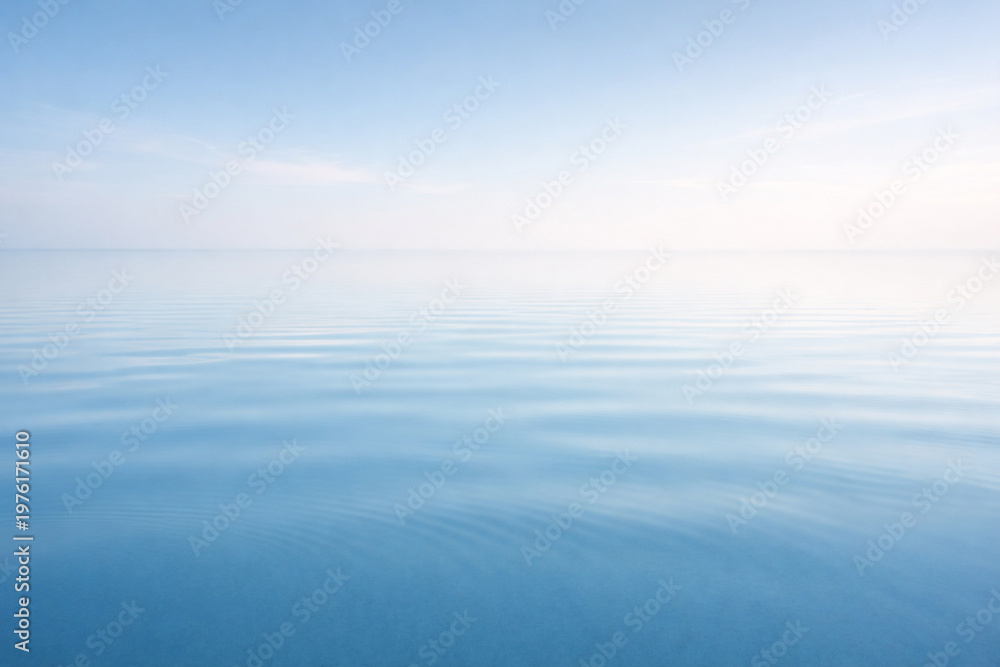 Fototapeta premium Serene Azure Horizon: A minimalist composition of tranquil water meeting a soft, diffused sky. This image evokes feelings of calmness, peace, and boundless freedom.
