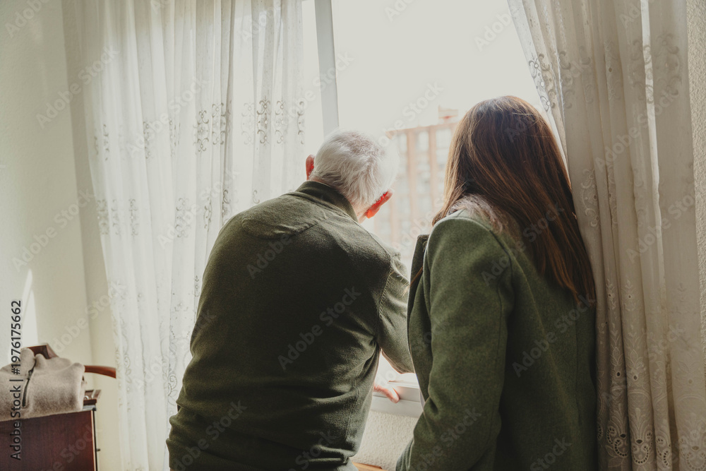 Fototapeta premium Senior man and adult daughter looking out window