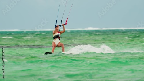 Sports woman kitesurfing in ocean in white bikini. Extreme summer sports