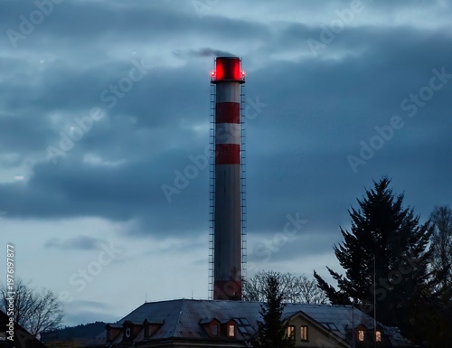 Obraz na płótnie Illuminated red signal tower oversees quiet village amid cloudy twilight skies a