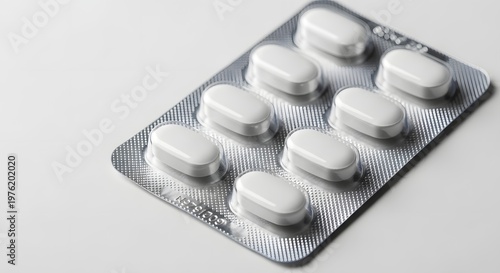 White pills in silver blister pack on clean white background healthcare pharmaceutical concept