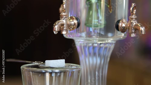 Slow motion absinthe preparation with dripping water on sugar cube