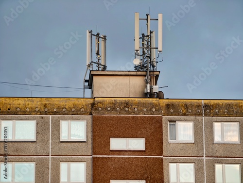 Telecommunication equipment installed on historic urban buildings under cloudy skies and mossy edges