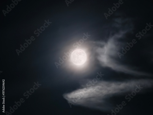 Fotografie Luminous moon surrounded by floating clouds casts gentle silver light over tranq