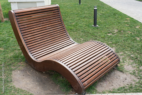 Wallpaper Mural Slatted Timber Lounger Beside Walkway, Contemporary Public Seating Element Placed On Grassy Verge Near Bollard And Paved Route, Clean Finish And Flowing Contour Encourage Social Pause, Photography Torontodigital.ca
