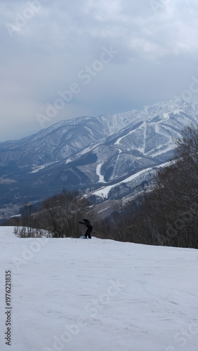 Snowboarder Riding Down Snowy Mountain Slope with Scenic Winter Resort Landscape