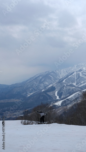 Snowboarder Jumps Over Snow Drift on Mountain Slope Amidst Winter Scenery