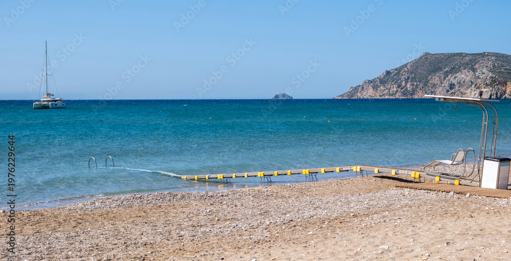 Fototapeta premium Accessible beach pathway with floating platform and handrails extending into blue sea, Chios island, Greece