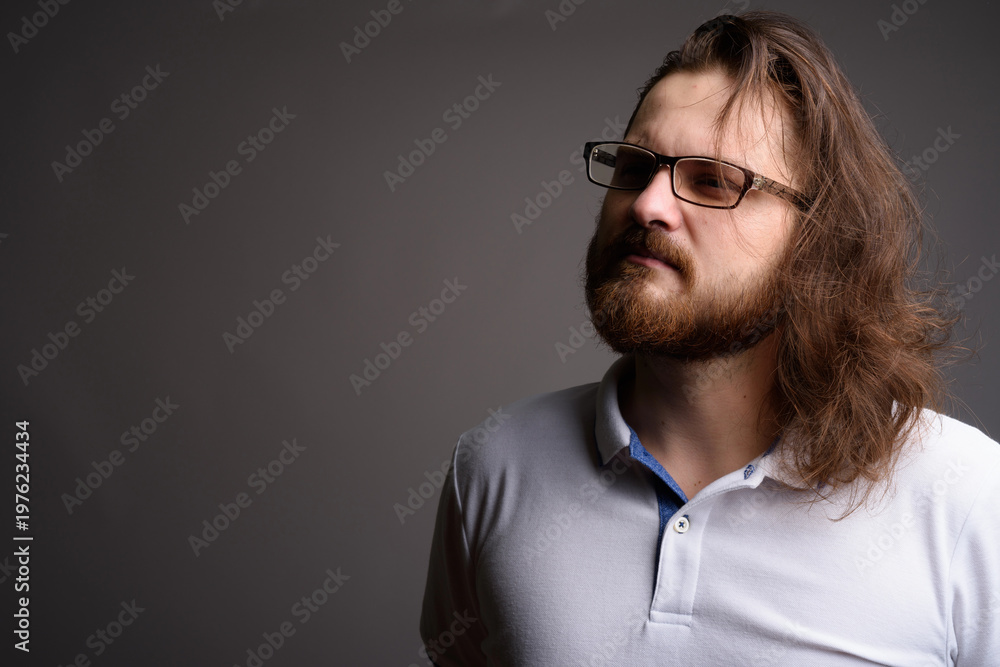 Obraz premium Pensive Bearded Man with Long Hair and Glasses Looking Away - Thinking Concept