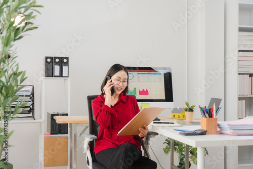 Business concept, Businesswoman is talking financial data with partner on smartphone at office.