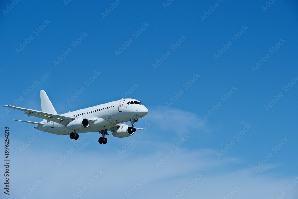 Obraz premium Commercial White Jet on Final Approach, Blue Sky with Light Clouds, Copy Space.