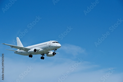 Commercial White Jet on Final Approach, Blue Sky with Light Clouds, Copy Space.