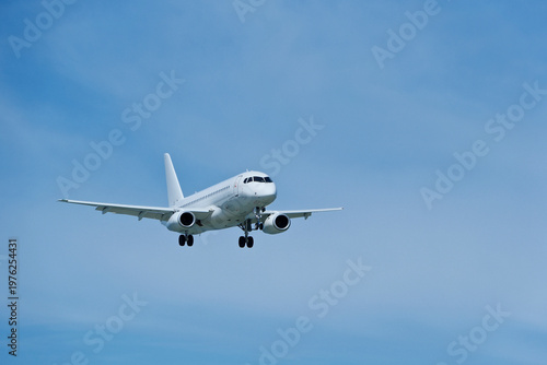 Commercial White Jet on Final Approach, Blue Sky with Light Clouds, Copy Space.