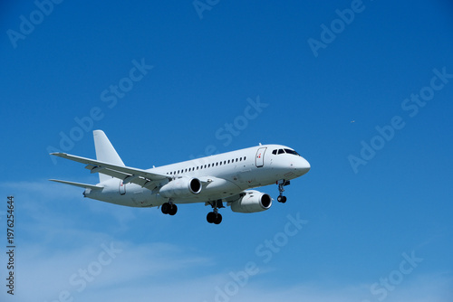 Commercial White Jet on Final Approach, Blue Sky with Light Clouds, Copy Space.