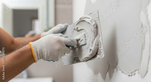 Manual repair process with hands applying plaster to wall using trowel. Manual repair involves smoothing out imperfections in wall surface with plaster,