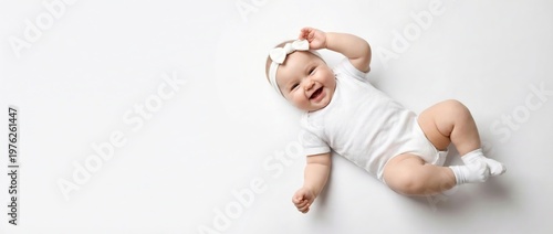 A baby wearing a white onesie and socks lies on their back with a toy above their face on a plain white background