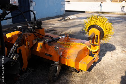Close up of street cleaning machine with rotating brush for road maintenance and urban sanitation work.