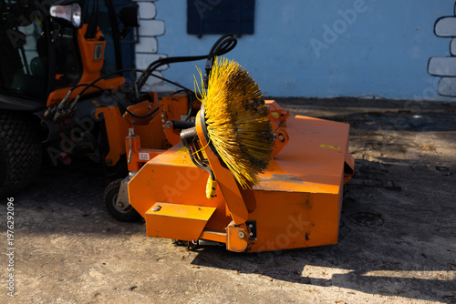 Close up of street cleaning machine with rotating brush for road maintenance and urban sanitation work.