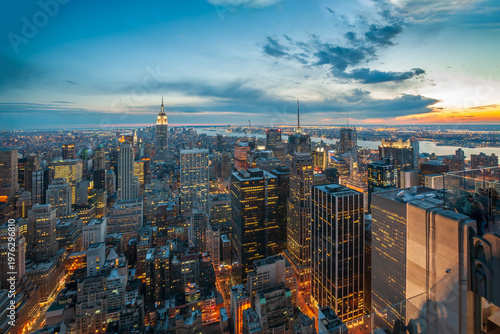 Aerial view of Manhattan skyline at sunset with illuminated skyscrapers and urban architecture in New York City, USA.