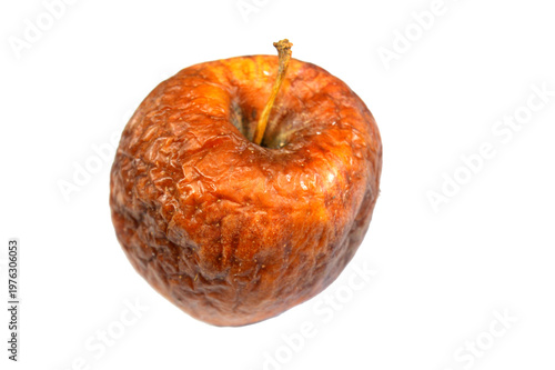a single decayed or rotten apple, The apple is wrinkled, dried out, and shows significant signs of decay and wastage with a reddish-brown color due to aging and spoilage, food waste concept