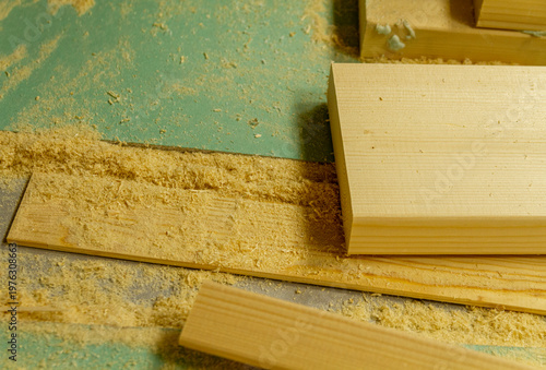 Obraz na płótnie The image shows a woodworking workshop scene with raw lumber pieces scattered on a workbench covered in sawdust, showcasing the process of constructing a mortise and tenon joint