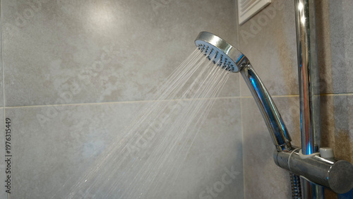 Water flows from a shower head in a bathroom during daytime hours