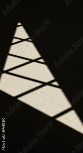 High contrast abstract geometric pattern created by sunlight casting stark, sharp shadows across a neutral textured surface, harsh, simple, angles