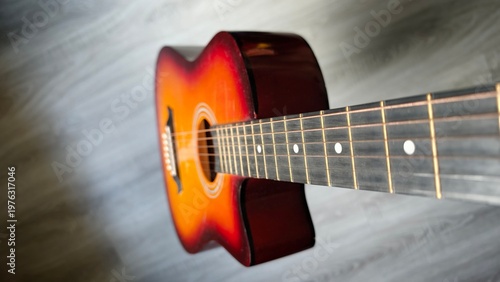 Foto Guitar sits on grey wood floor in bright light while a melody plays nearby