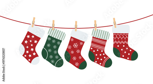 Five festive socks in red and green colors with star snowflake and stripe patterns. Holiday laundry line concept with decorative footwear attached by clips on white background.