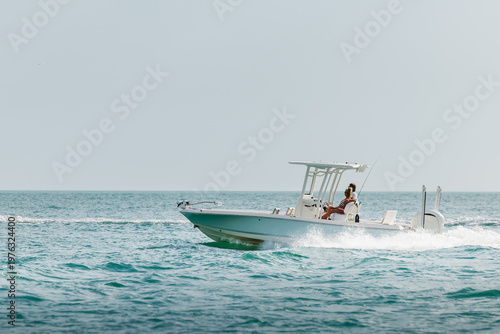 Saltwater fishing boat on a sunny summer day. Couple on recreational powerboat cruising the blue water of the Gulf of America, Florida.