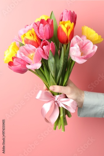 Woman with bouquet of aromatic bright tulips on pink background, closeup. Beautiful greeting card