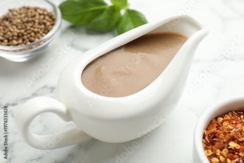 Tableau sur toile Turkey gravy in sauce boat on white marble table, closeup