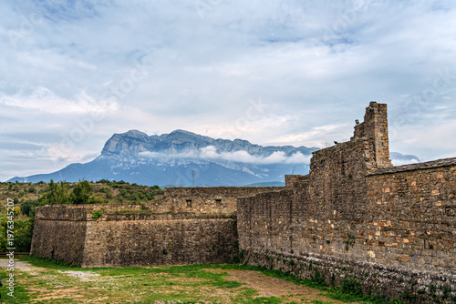 Ainsa Castle in the medieval village of Ainsa in Spain surrounded by stone walls with an elevated path leading to it.