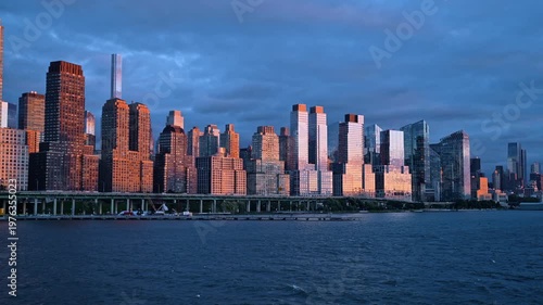 Light of setting sun on the facades of glass skyscrapers. View on the towers of Manhattan from the river at sunset.