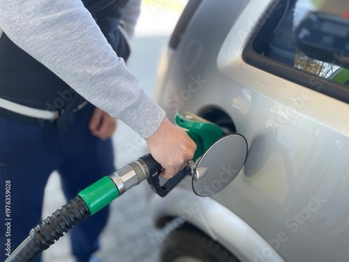 Fotografie A detailed close-up shot capturing a person’s hand holding a green fuel pump noz