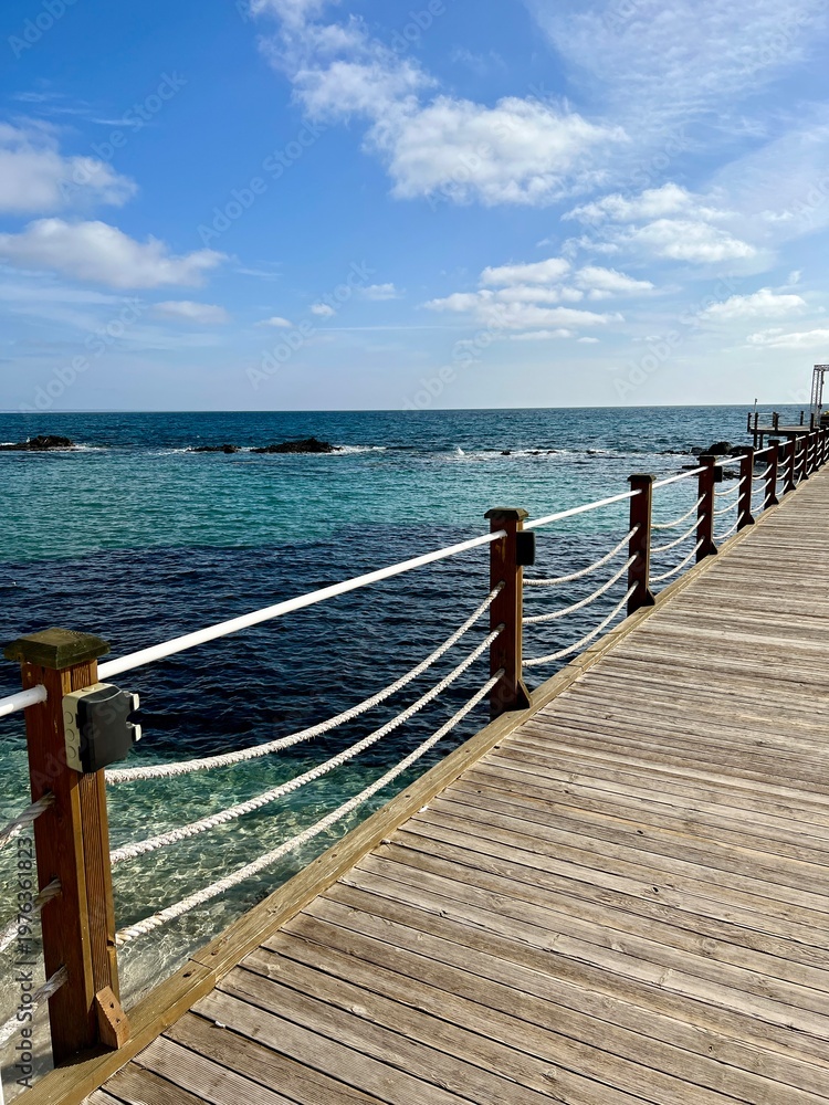 Fototapeta premium Wooden pier with rope railings leading to the turquoise Mediterranean Sea in Cyprus