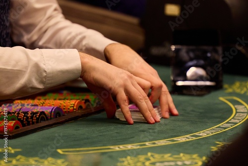 Casino dealer shuffling cards at blackjack table with poker chips