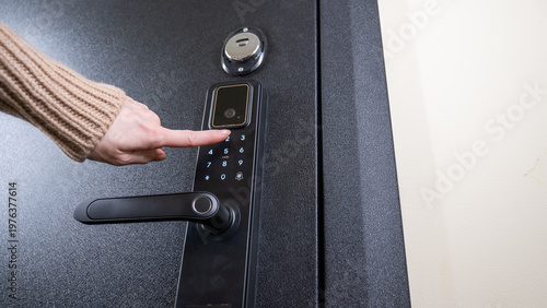Canvastavla A woman opens a modern smart door lock with a digital keypad using a code