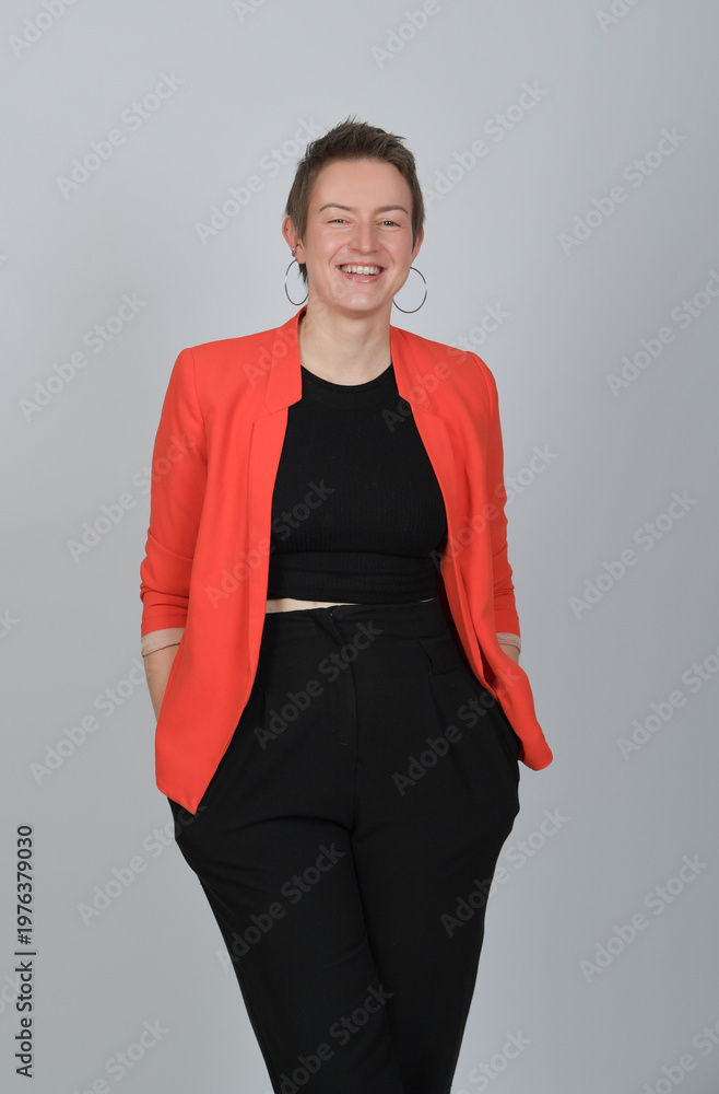 Fototapeta premium Selbstbewusste Geschäftsfrau im roten Blazer vor neutralem Hintergrund, modernes Business-Porträt mit Ausstrahlung und Copyspace