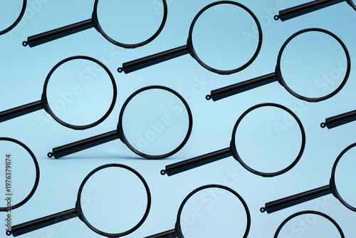 A pattern of black magnifying glasses on a light blue background. The glasses are arranged in a repetitive design, creating a visually striking effect.