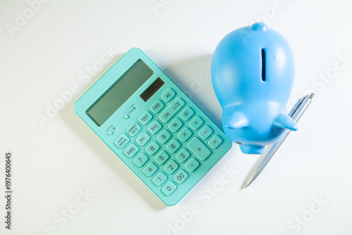 Blue piggy bank with calculator and pen on a white background.