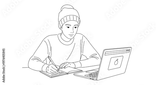 A young person in a beanie deeply focused while working on a laptop, simultaneously taking notes on a notepad.