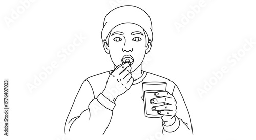 A young man is thoughtfully taking a pill with a glass of water, demonstrating responsible medication use or health supplements.